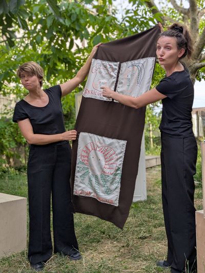 Les comédiennes de Dame ! montrant des personnages historiques sur un drap tissé